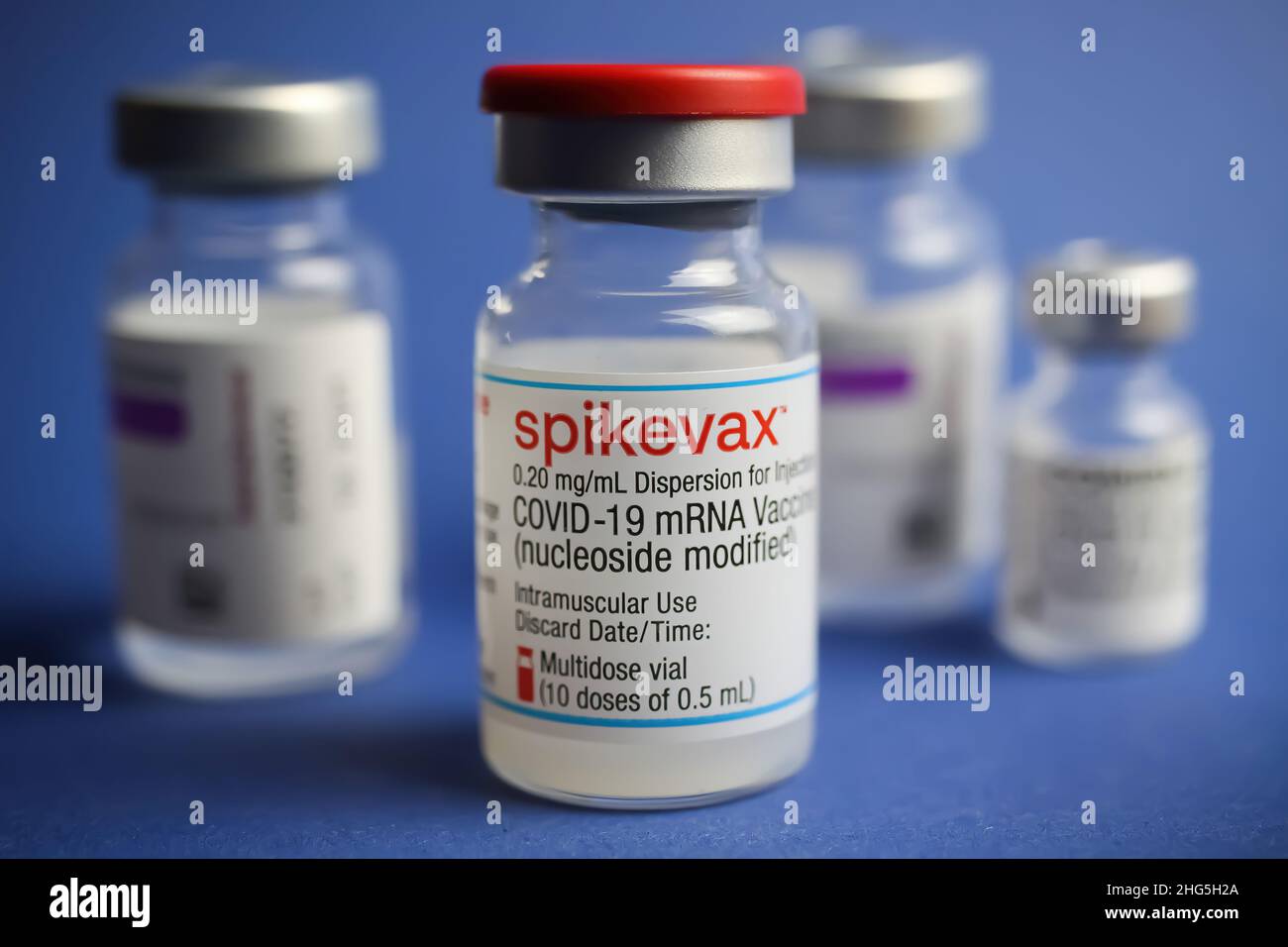 Viersen, Deutschland - Januar 9. 2022: Nahaufnahme von Gruppenfläschchen Covid-19 Impfserum, blauer Hintergrund Stockfoto