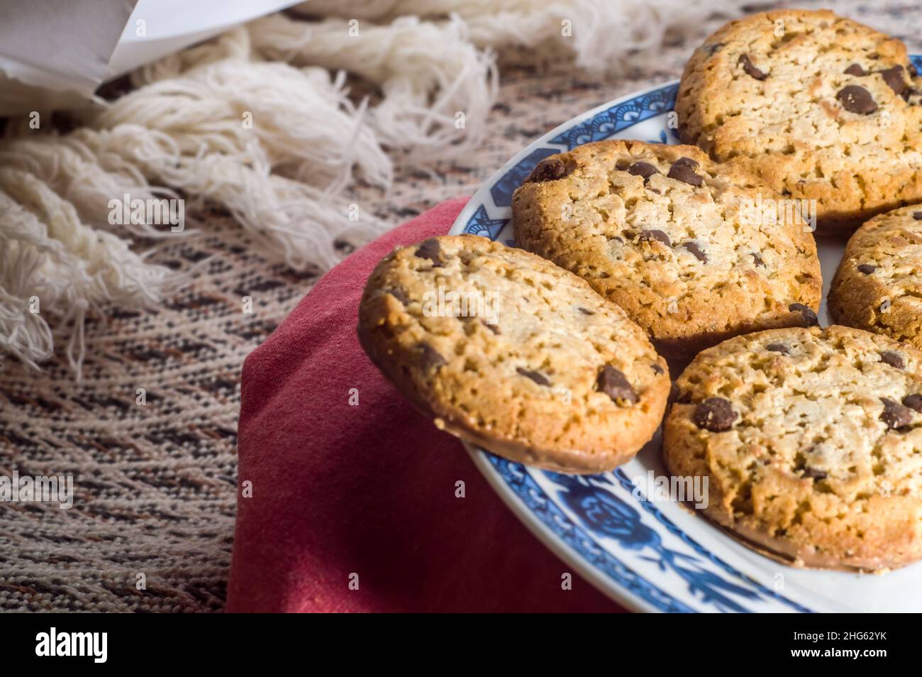 Kekse auf einem Teller mit verschwommener Tasse im Hintergrund und herabfallenden Kaffeetropfen, Platz zum Kopieren Stockfoto