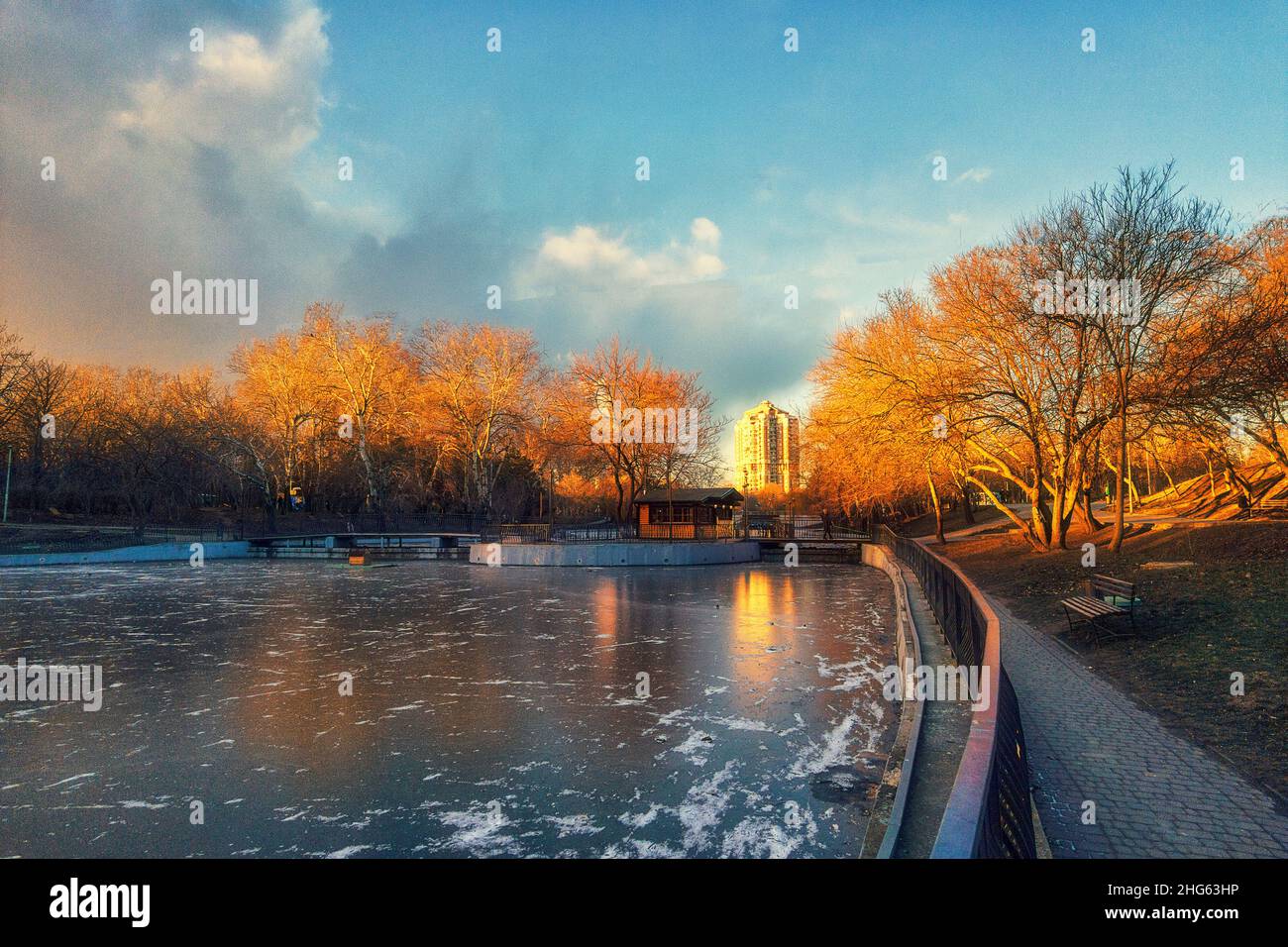 Winter Stadtpark bei Sonnenuntergang und ein gefrorener See mit Bäumen ohne Blätter Stockfoto