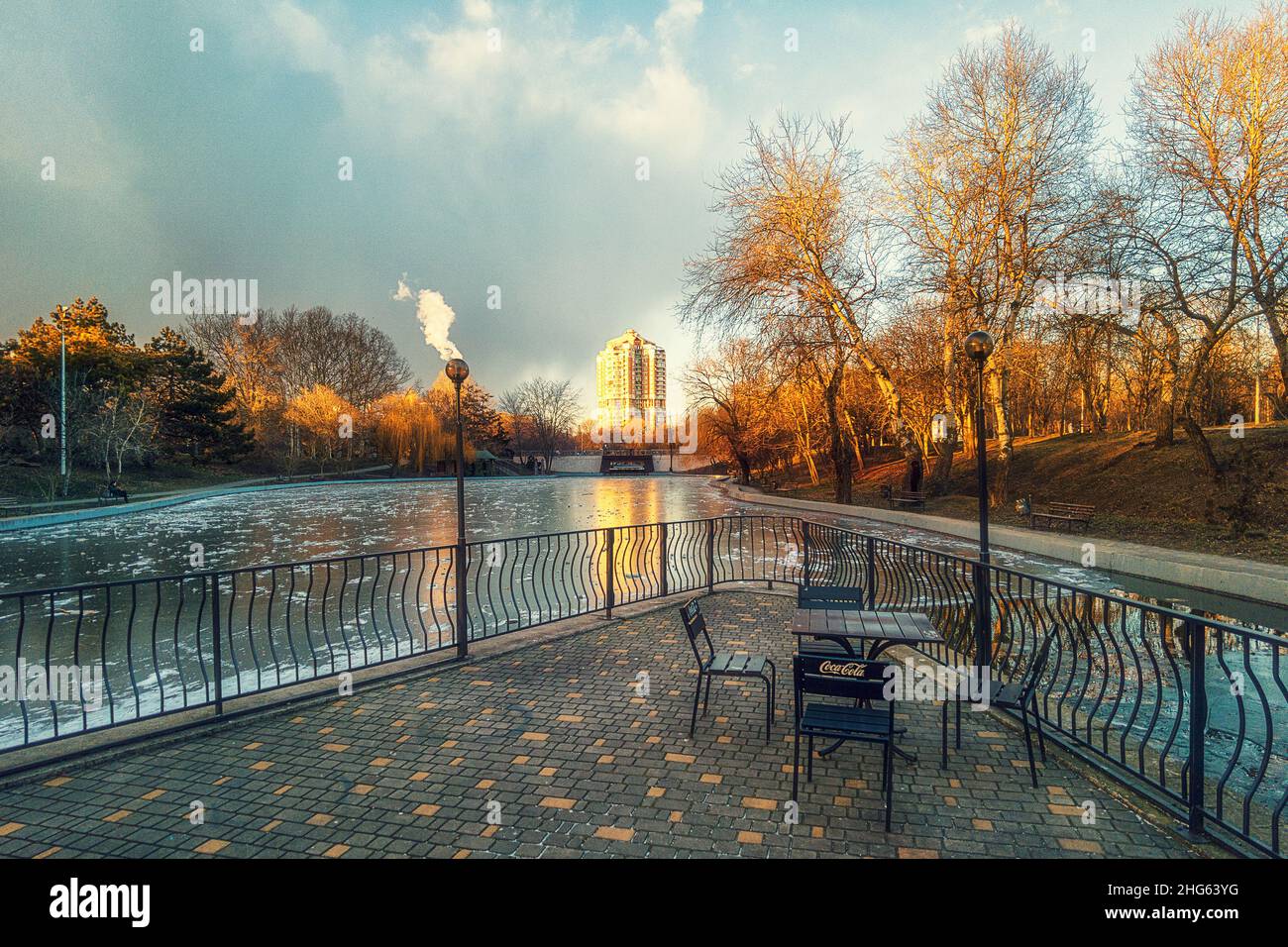 Winter Stadtpark bei Sonnenuntergang und ein gefrorener See mit Bäumen ohne Blätter Stockfoto