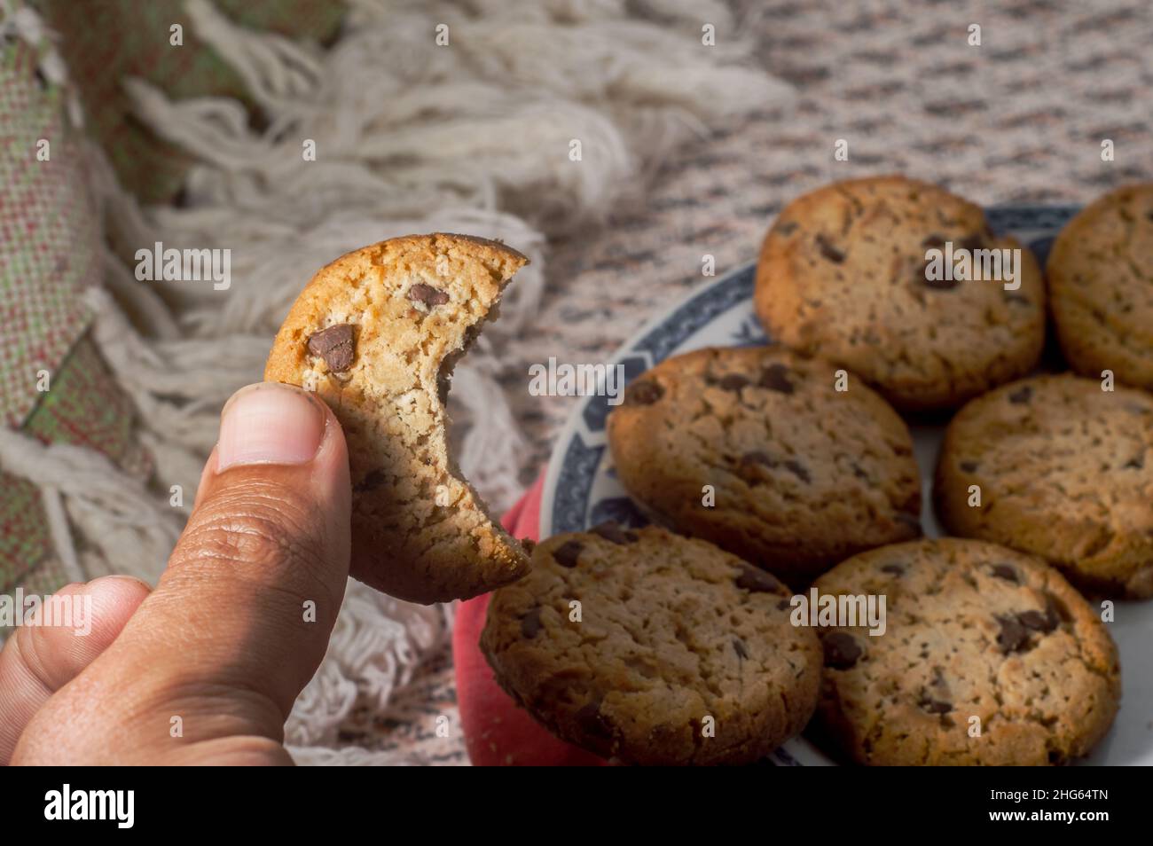 Kekse auf einem Teller mit verschwommener Tasse im Hintergrund und herabfallenden Kaffeetropfen, Platz zum Kopieren Stockfoto