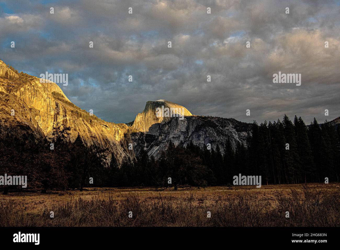 Sonnenaufgang mit dramatischem Morgensonnenlicht am Half Dome im Yosemite-Nationalpark mit verstreuten Wolken Stockfoto