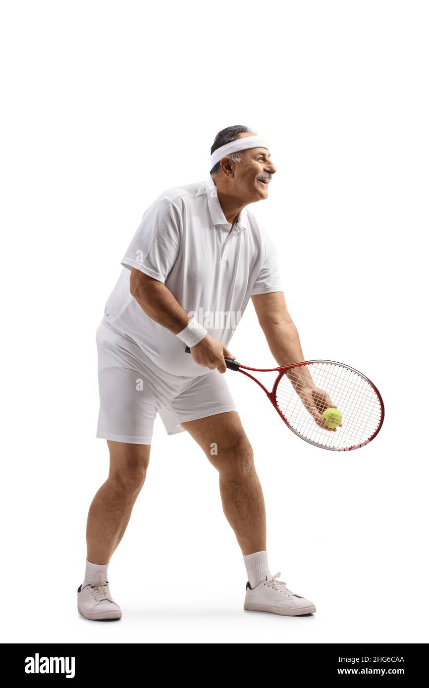 In voller Länge Profilaufnahme eines reifen Mannes, der Tennis spielt und auf weißem Hintergrund einen Aufschlag startet Stockfoto