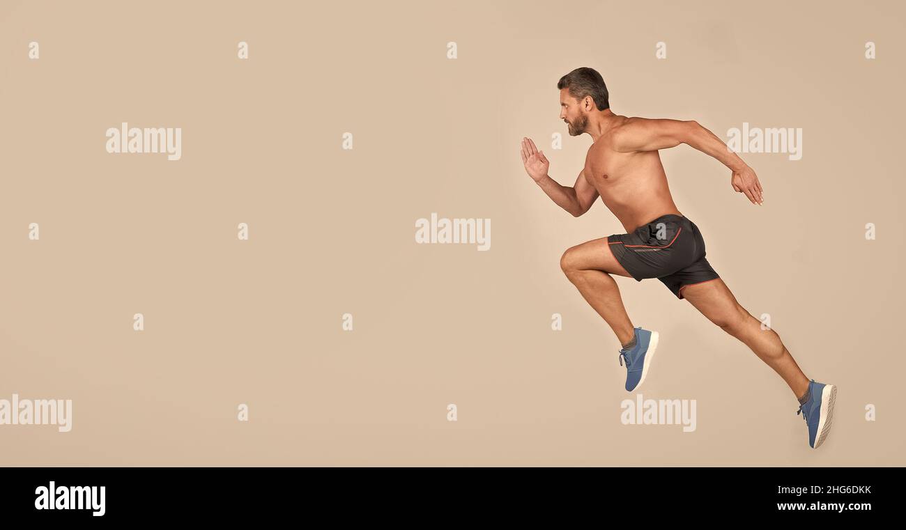 Sportler Mann Läufer laufen zum Erfolg oder springen hoch auf grauem Hintergrund, kopieren Raum, Sport Stockfoto