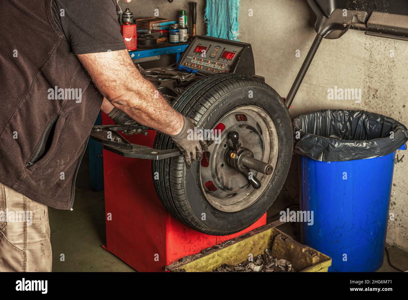Mann, der Handwerkzeuge verwendet, um ein Rad in einer Garage zu balancieren Stockfoto