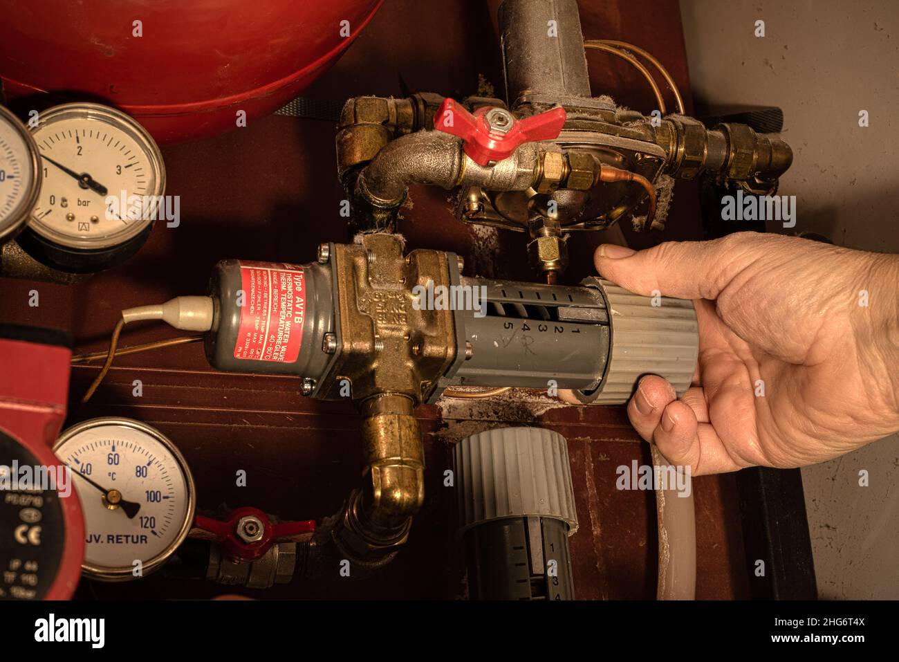 Eine Hand dreht den Knopf auf dem Regler auf ein Fernwärmesystem, Dänemark, 18. Januar 2022 Stockfoto