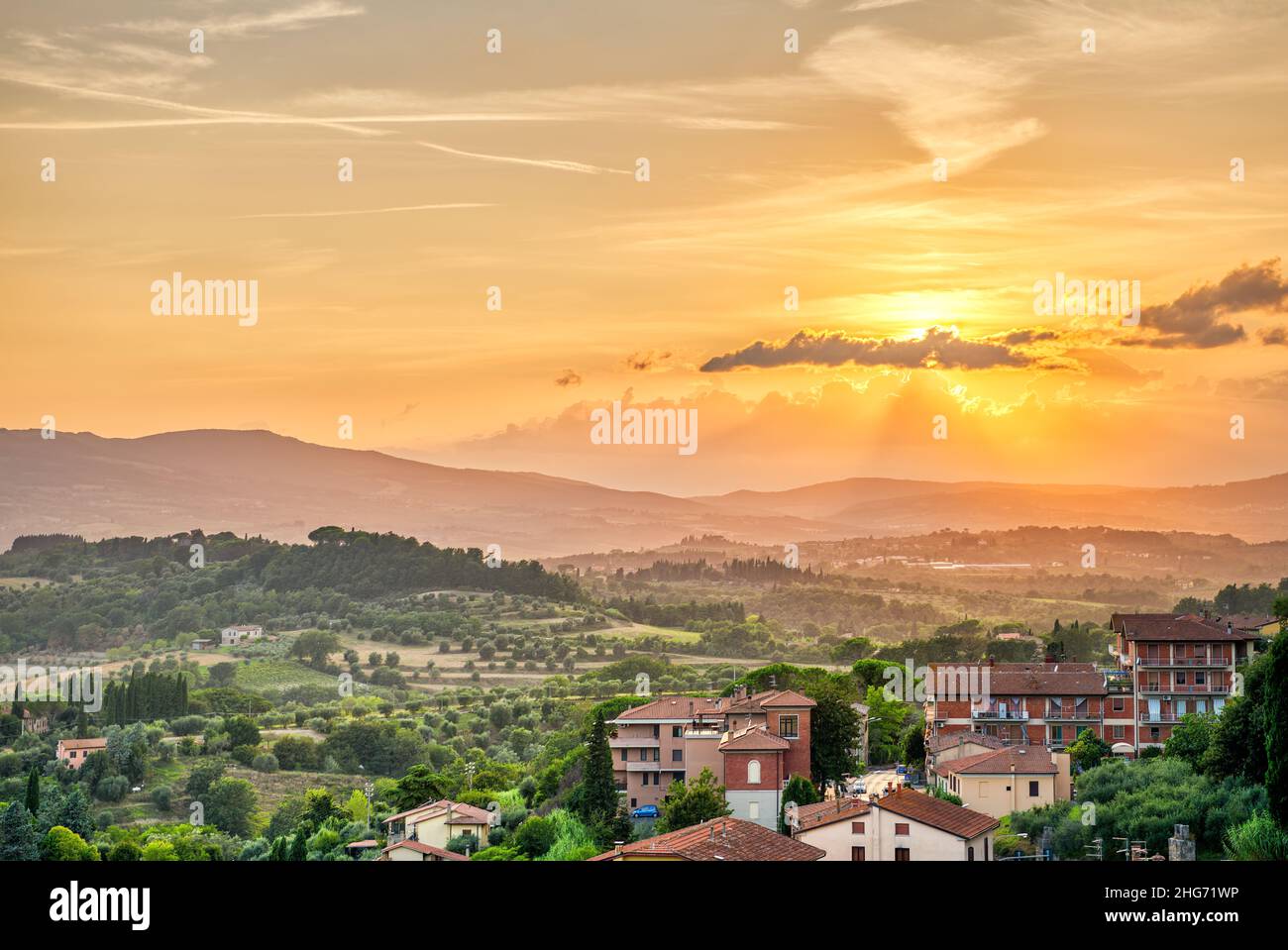 Sonnenuntergang im kleinen Dorf Chiusi Toskana Italien mit Häusern Dächer auf Berglandschaft sanfte Hügel Landschaft und orange gelbe Farbe Stockfoto