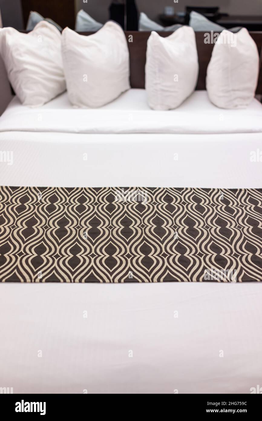 Schlafzimmer in der Nacht mit vier weißen Kissen und Laken auf Matratze Bett in modernen Hotel Motelzimmer mit niemand und stilvolles Dekor vertikal abstrakt vi Stockfoto