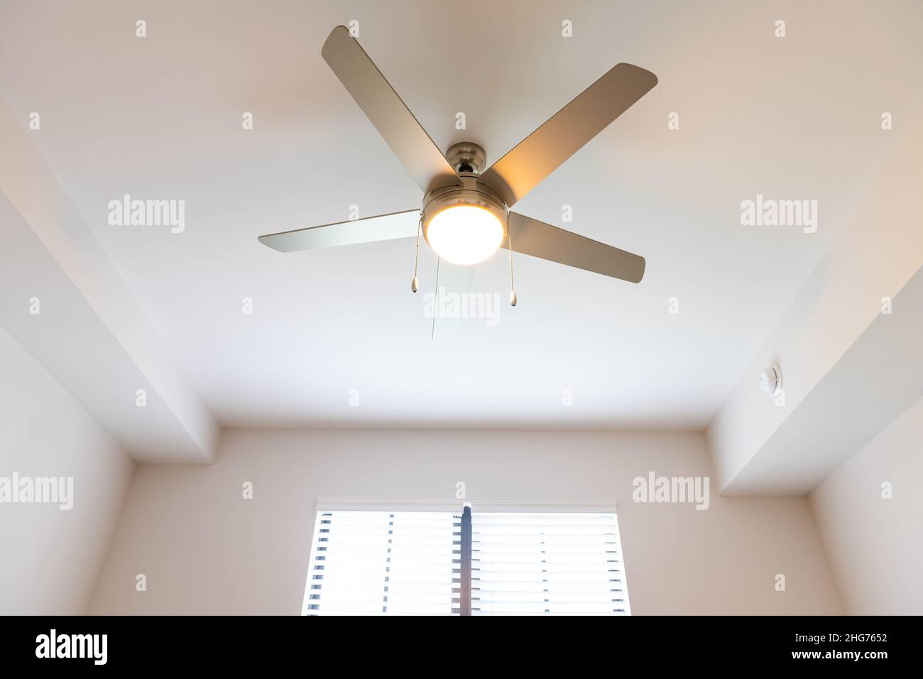 Leeres Schlafzimmer Zimmer innen niemand blickte aus dem Winkel auf beleuchtet gelbes Licht Deckenventilator Fenster in neuen modernen Luxus-Wohnung Haus ho Stockfoto