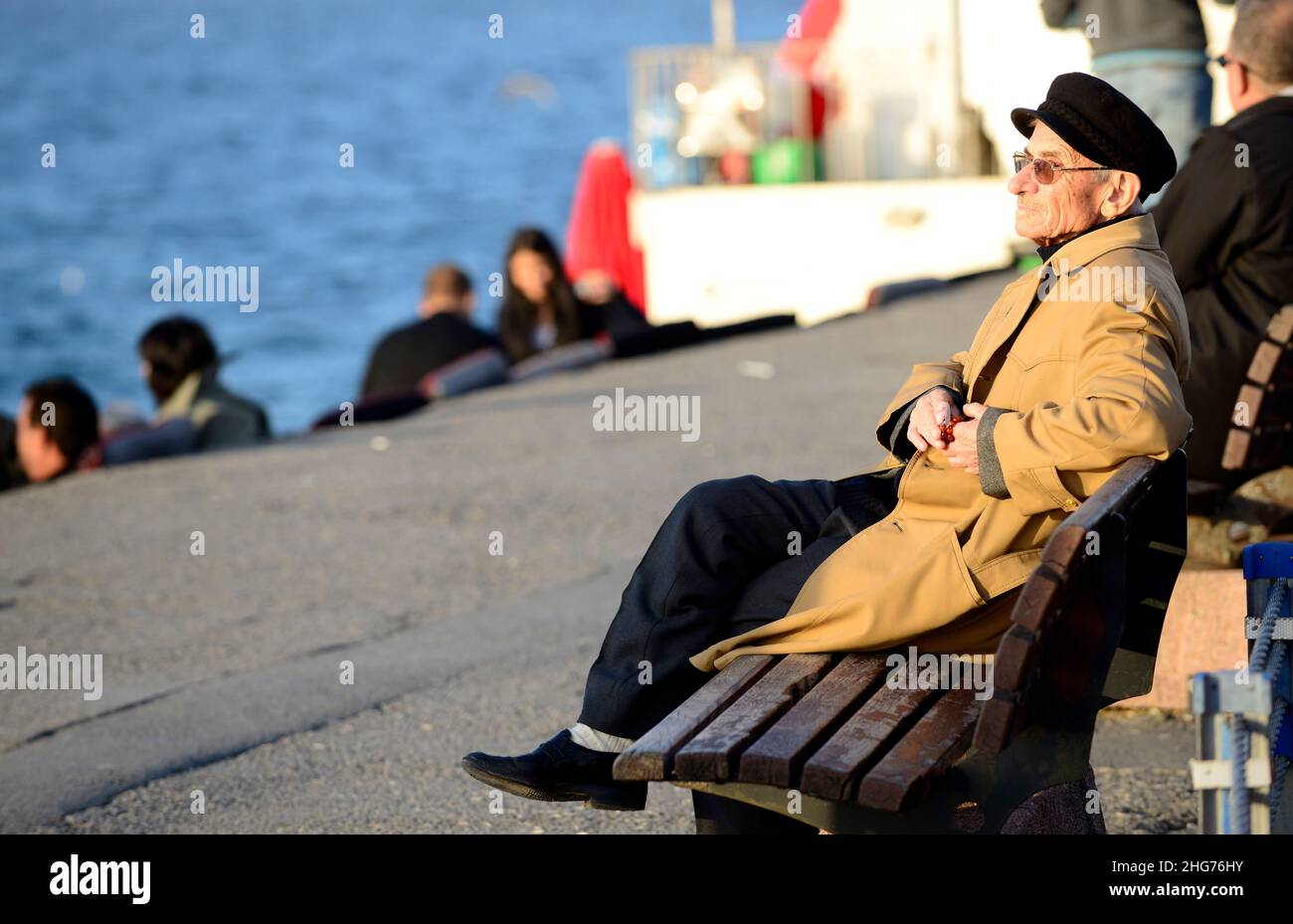 Ein älterer türkischer Mann, der die Sonne auf der Uferpromenade der Uskudar-Küste entlang der Bosporus-Meerenge auf der asiatischen Seite Istanbuls, Türkei, einweicht Stockfoto