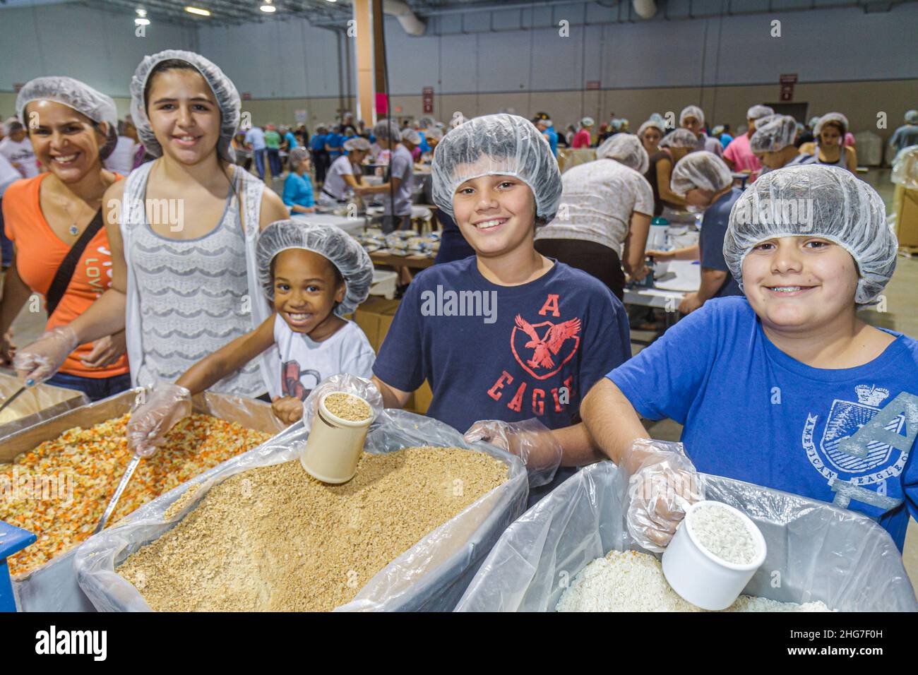 Florida, Miami Feed Meine hungernden Kinder Freiwillige Freiwilligenarbeit, Teamarbeit Verpackung Mahlzeiten, Hispanic Schwarze weibliche Teenager-Mädchen Jungen Studenten tragen Haarnetz Stockfoto