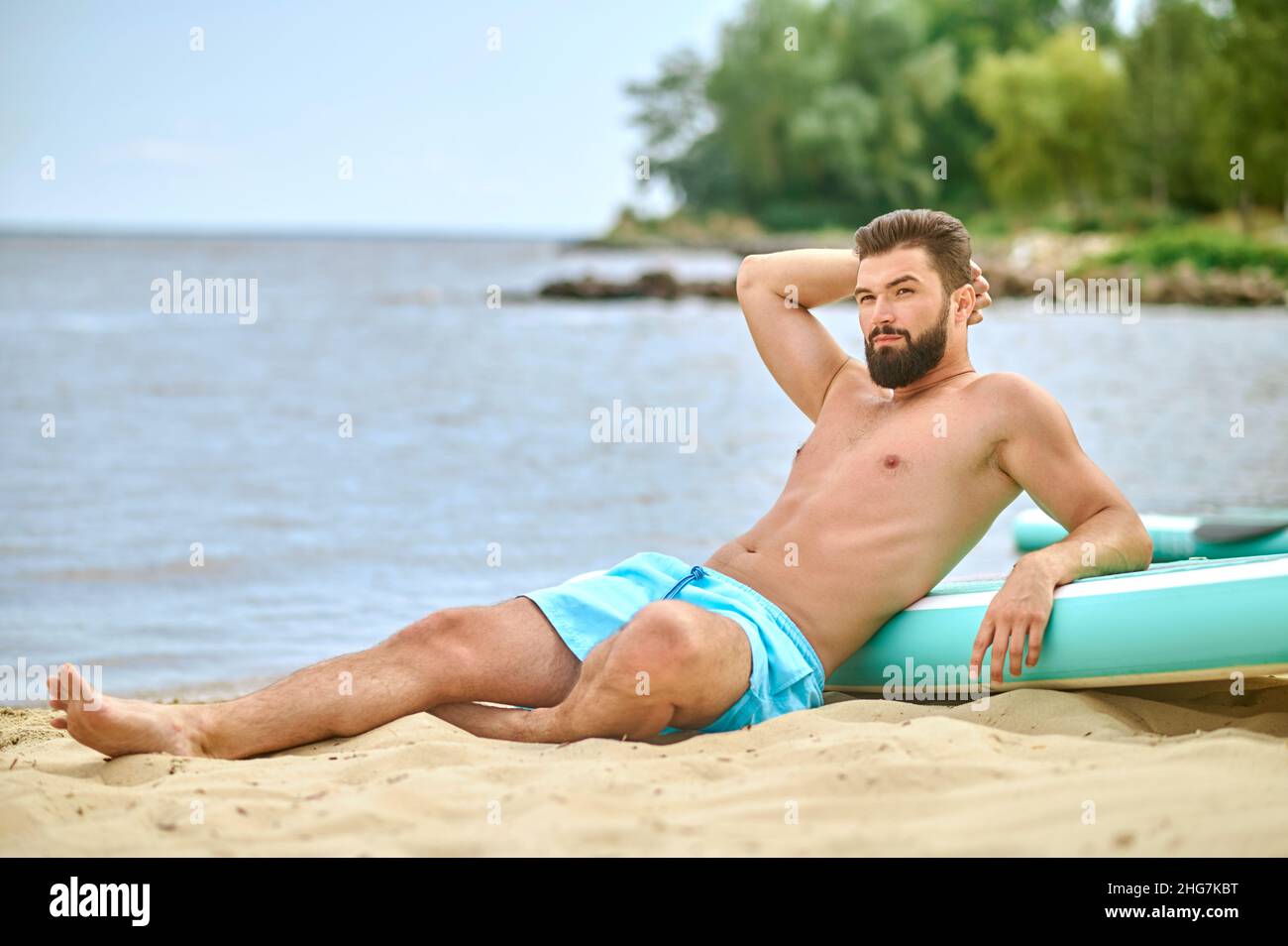Ein Mann in blauen Badeshorts, der am Strand liegt Stockfoto