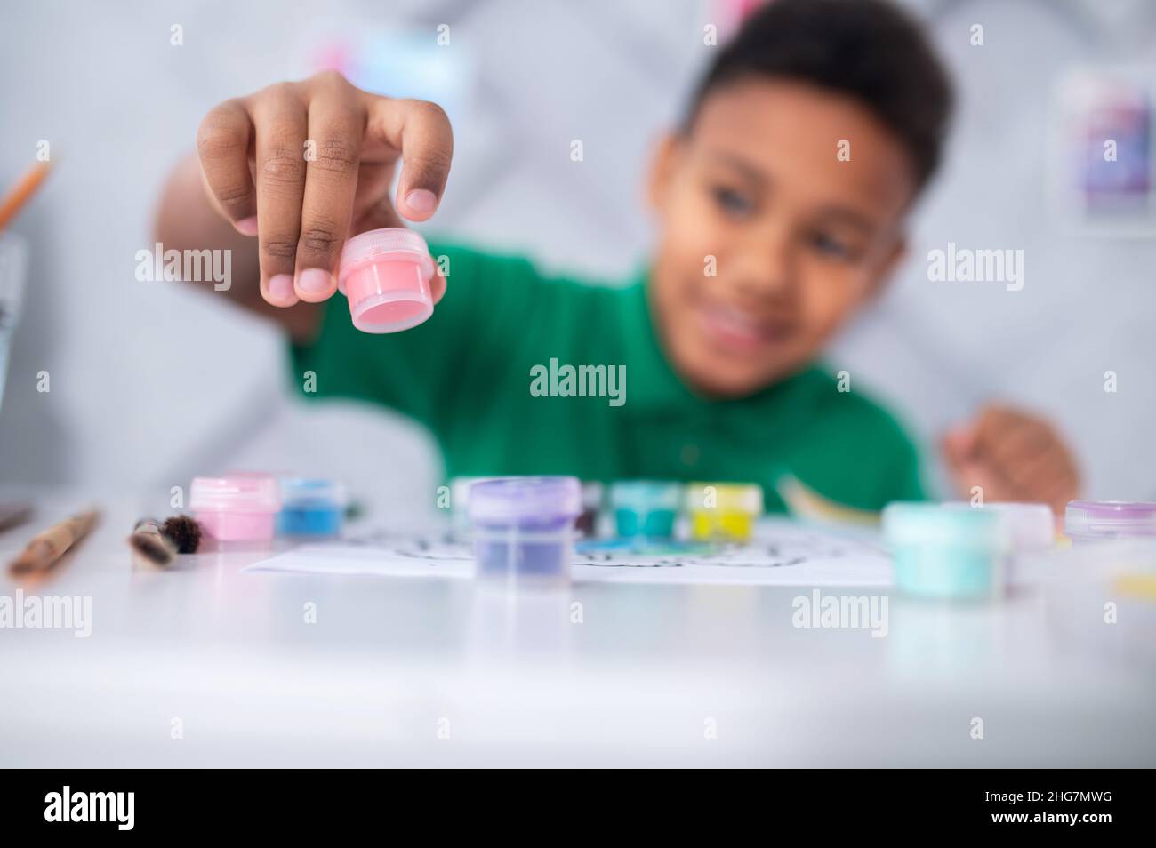 Junge streckt die Hand mit einem Farbtubus zur Kamera Stockfoto