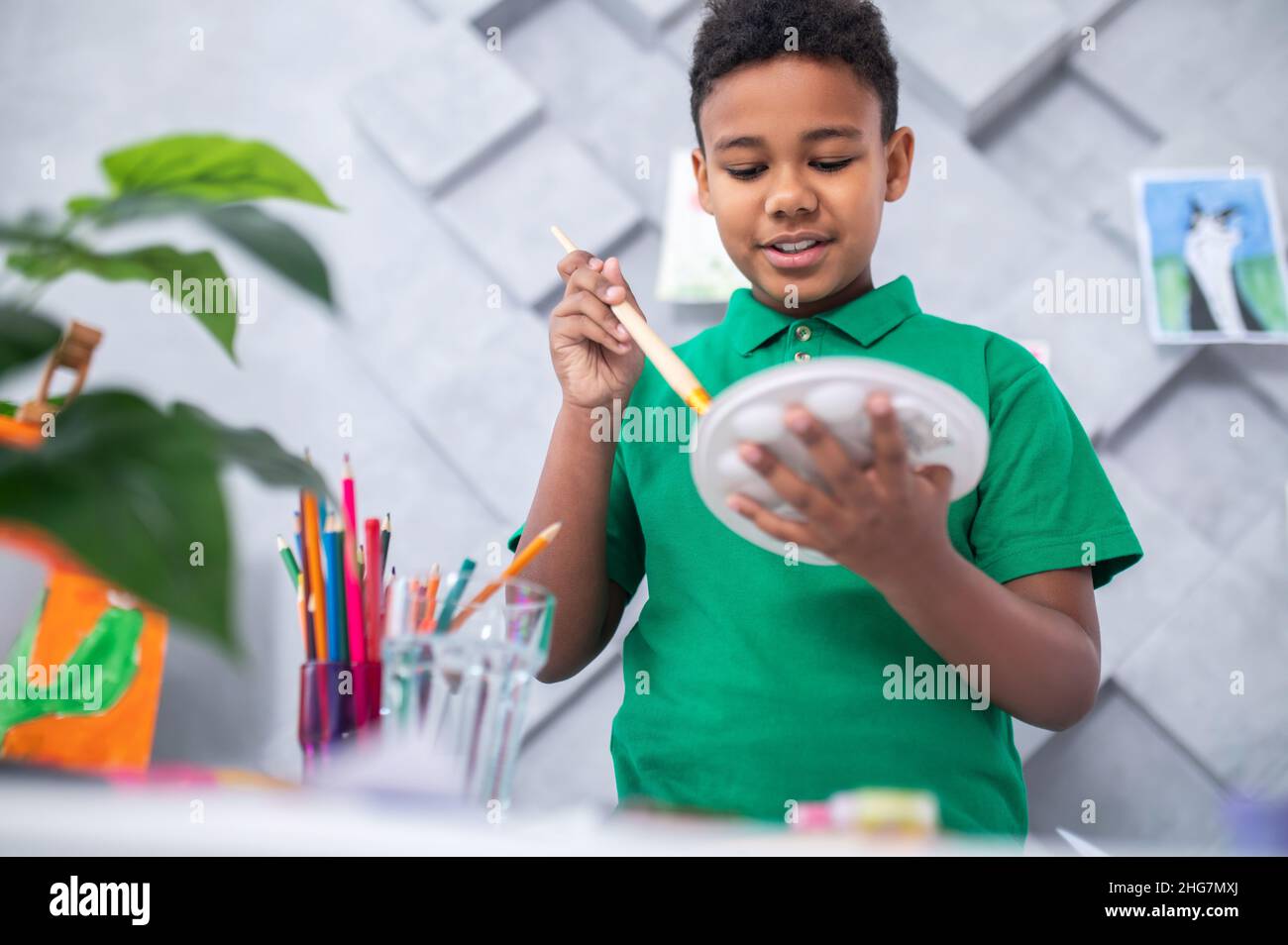 Junge berühren Palette mit Pinsel in der Hand Stockfoto