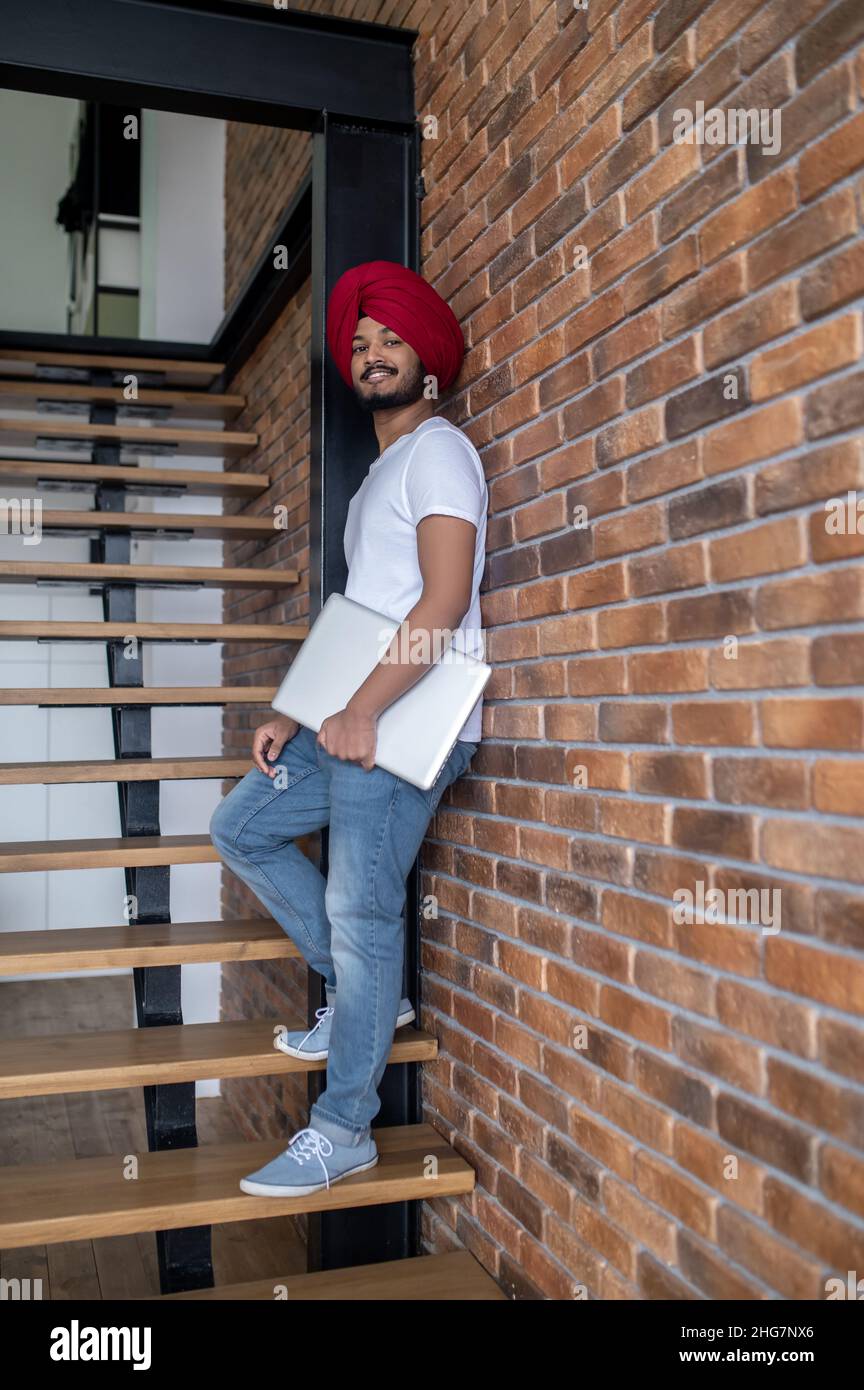 Junger inder im roten Turban, der auf Treppen steht Stockfoto