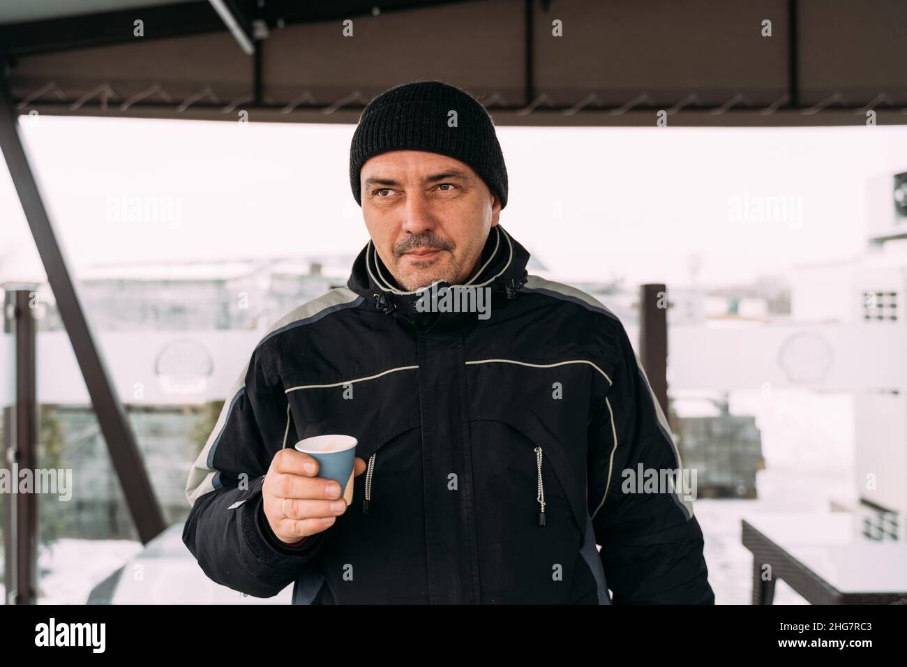 Männlicher Mann trinkt Kaffee aus dem Papierbecher während des kalten Wintertages Stockfoto