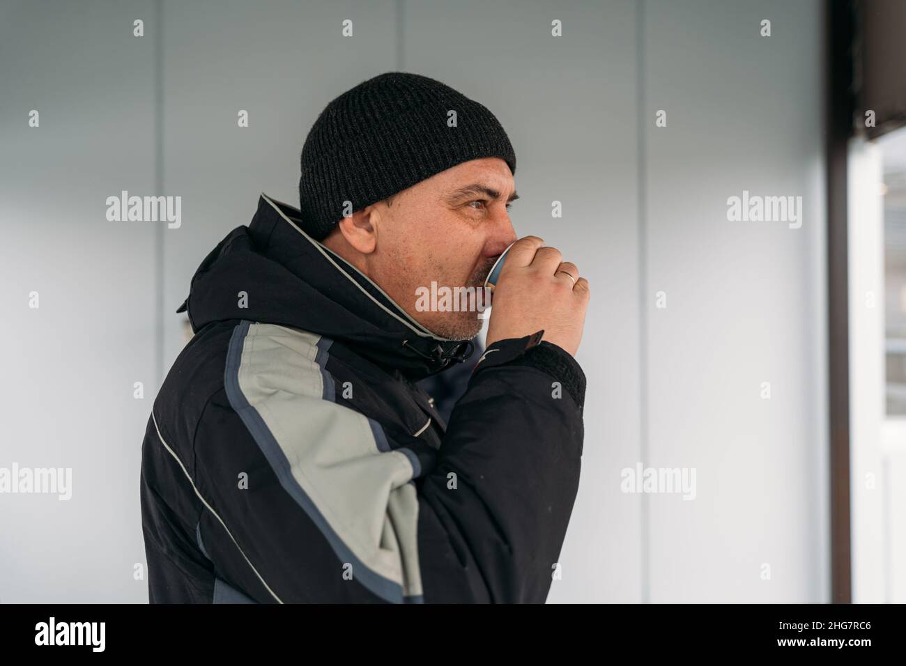 Mann im mittleren Alter, der an einem kalten Tag im Freien Kaffee trinkt Stockfoto