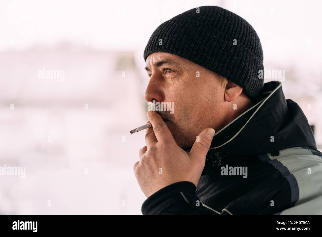 Mann im mittleren Alter, der an einem kalten Tag im Freien Zigarette raucht Stockfoto