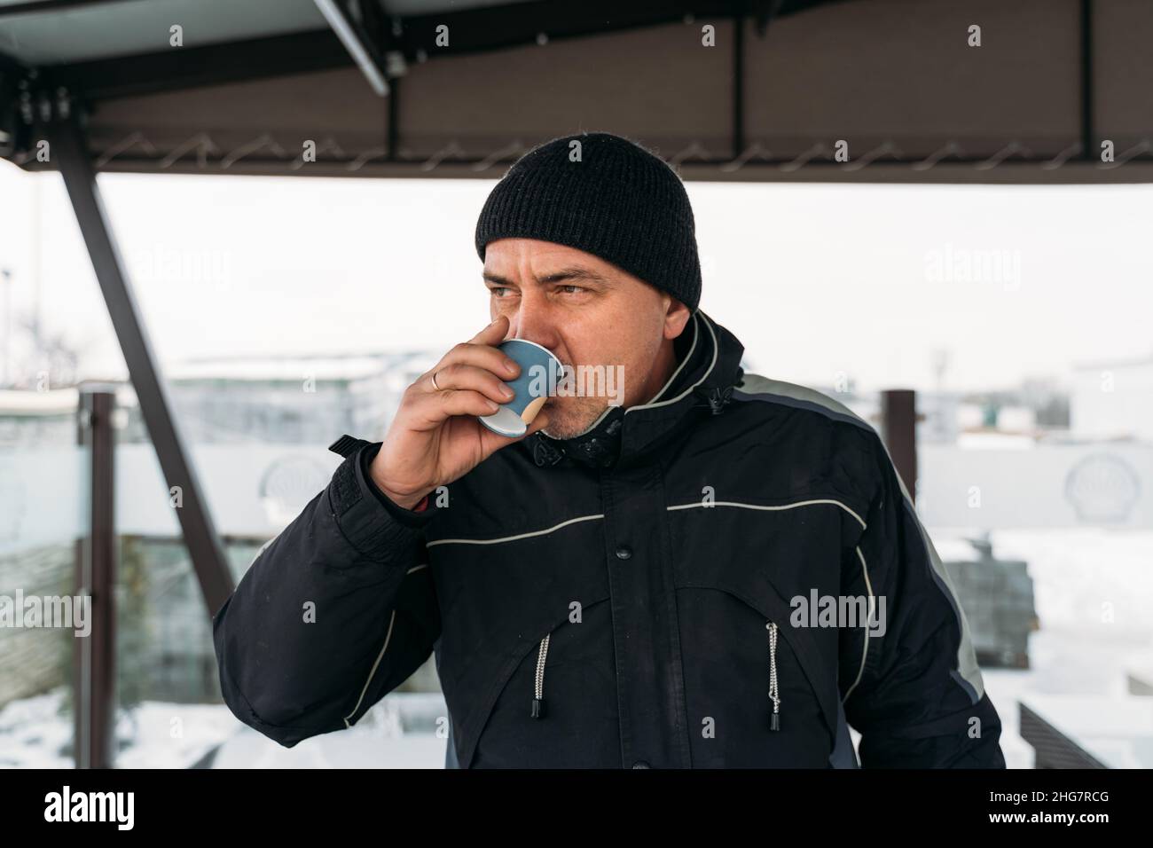 Mittelalter brutaler Mann, der an einem kalten Tag im Freien Kaffee trinkt Stockfoto