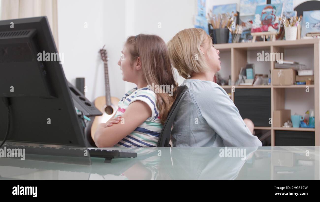 Mutter und Tochter stehen sich zurück und streiten für Schulnoten. Verärgert besorgt Eltern kämpfen mit Kind, während sie am Schreibtisch im Wohnzimmer sitzen Schwierigkeiten. Konzept der verärgerten Familie Stockfoto