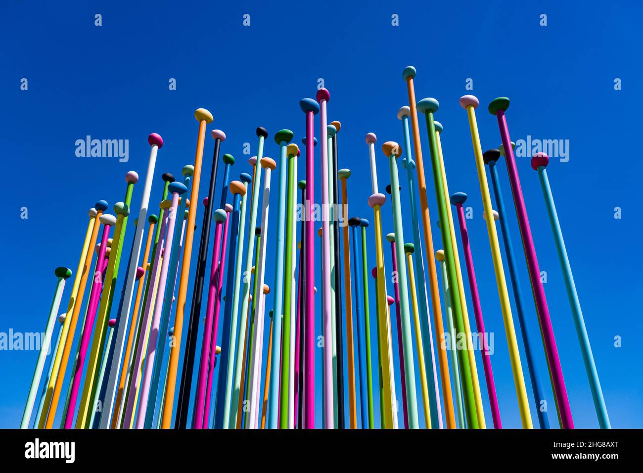 Farbige Stöcke mit einer Kugel oben ragen in den blauen Himmel, ein Kunstprojekt im Stadtteil Porta Nuovo. Stockfoto