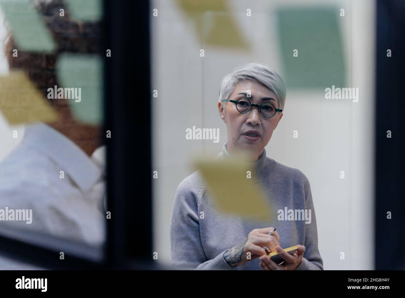 Senior Asian Company Manager Brainstorming im Tagungsraum, während Haftnotizen auf Glas im Büro. Kooperation und Teamwork Diversity Konzept Stockfoto