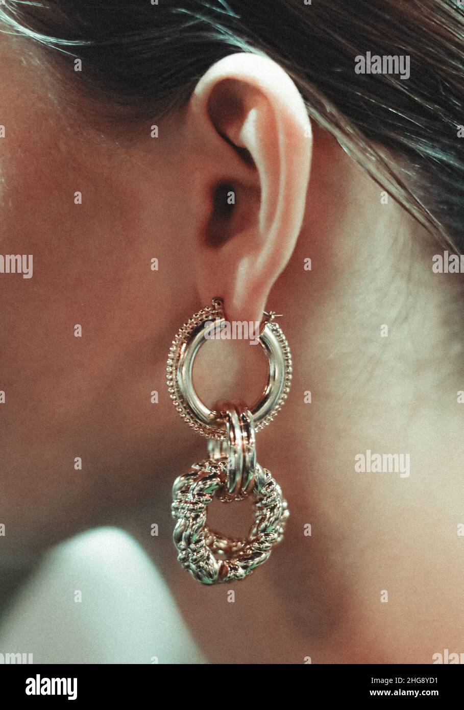 Großer goldener, kreativer Ohrring im Frauenohr. Modische Accessoires Stockfoto