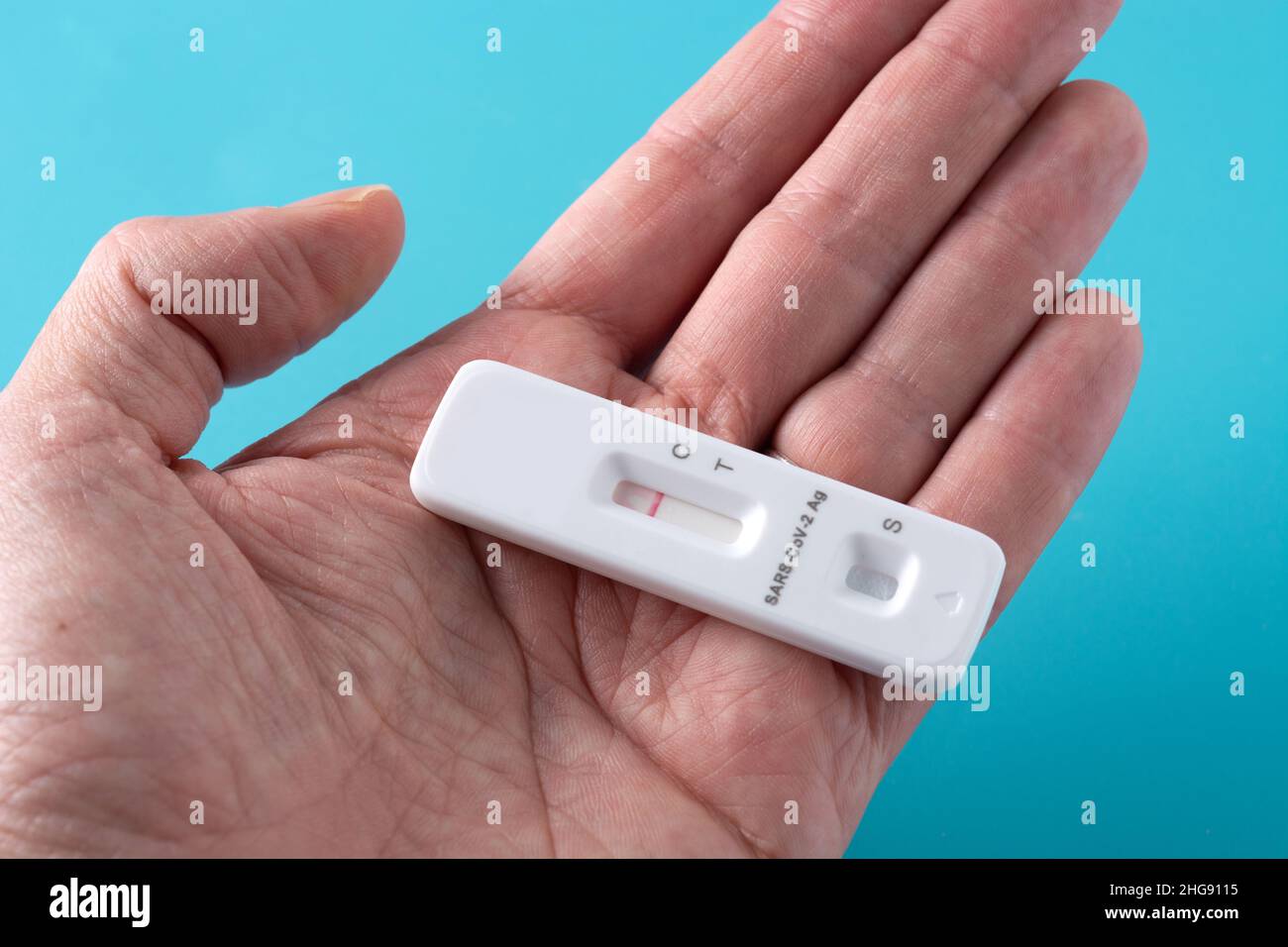 Hand mit Covid-19 Schnellantigen-Test auf blauem Hintergrund Stockfoto