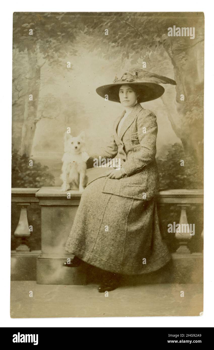 Original Titanic / späten Edwardian Ära Studio Portrait Postkarte von attraktiven Dame in großen Hut trägt eine modische Jacke und Rock, mit Terrier Hund, stammt aus ca. 1911 Studio von Woodwards, Guernsey. Stockfoto