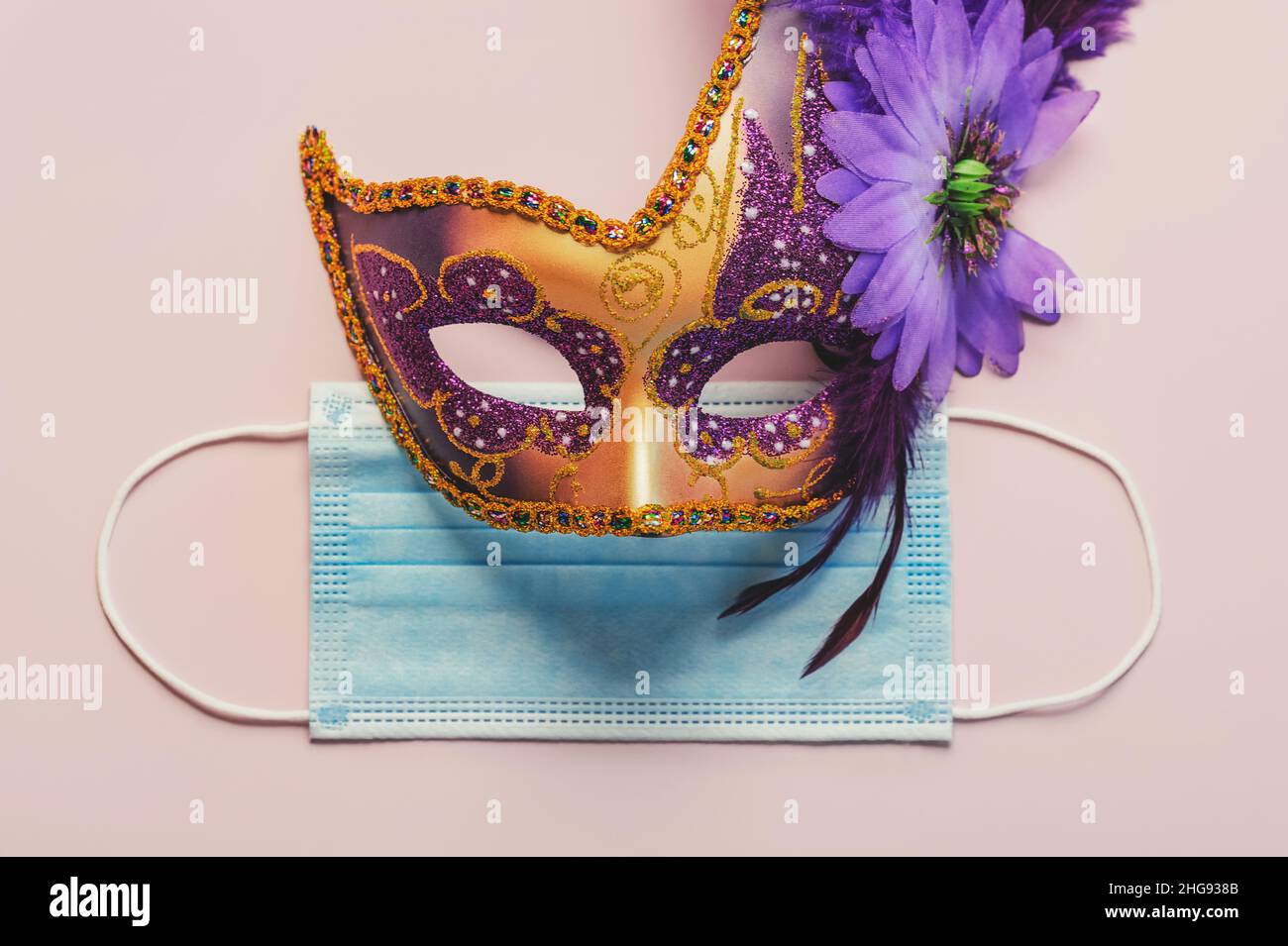 Konzept des Karnevals während des Covid-19. Venezianische Karnevalsmaske mit schützender OP-Maske auf hellem Hintergrund. Konzept der Karnevalsfeier Stockfoto