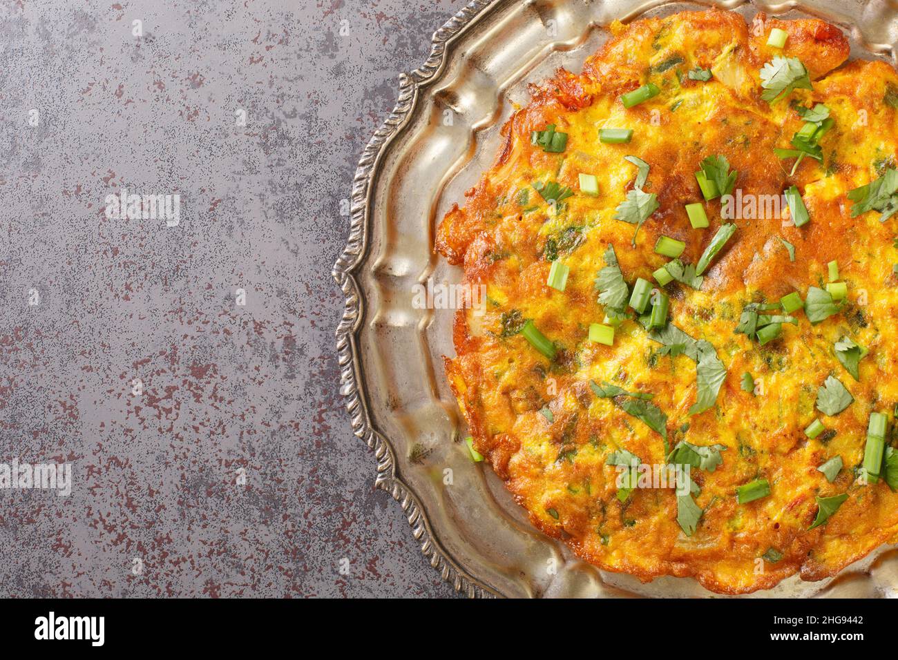 Gebratene Veggie Omelette mit gemischtem Gemüse umrühren. Indische nepalesische Stil Masala Omelet Nahaufnahme in der Platte auf dem Tisch. Horizontale Draufsicht von oben Stockfoto