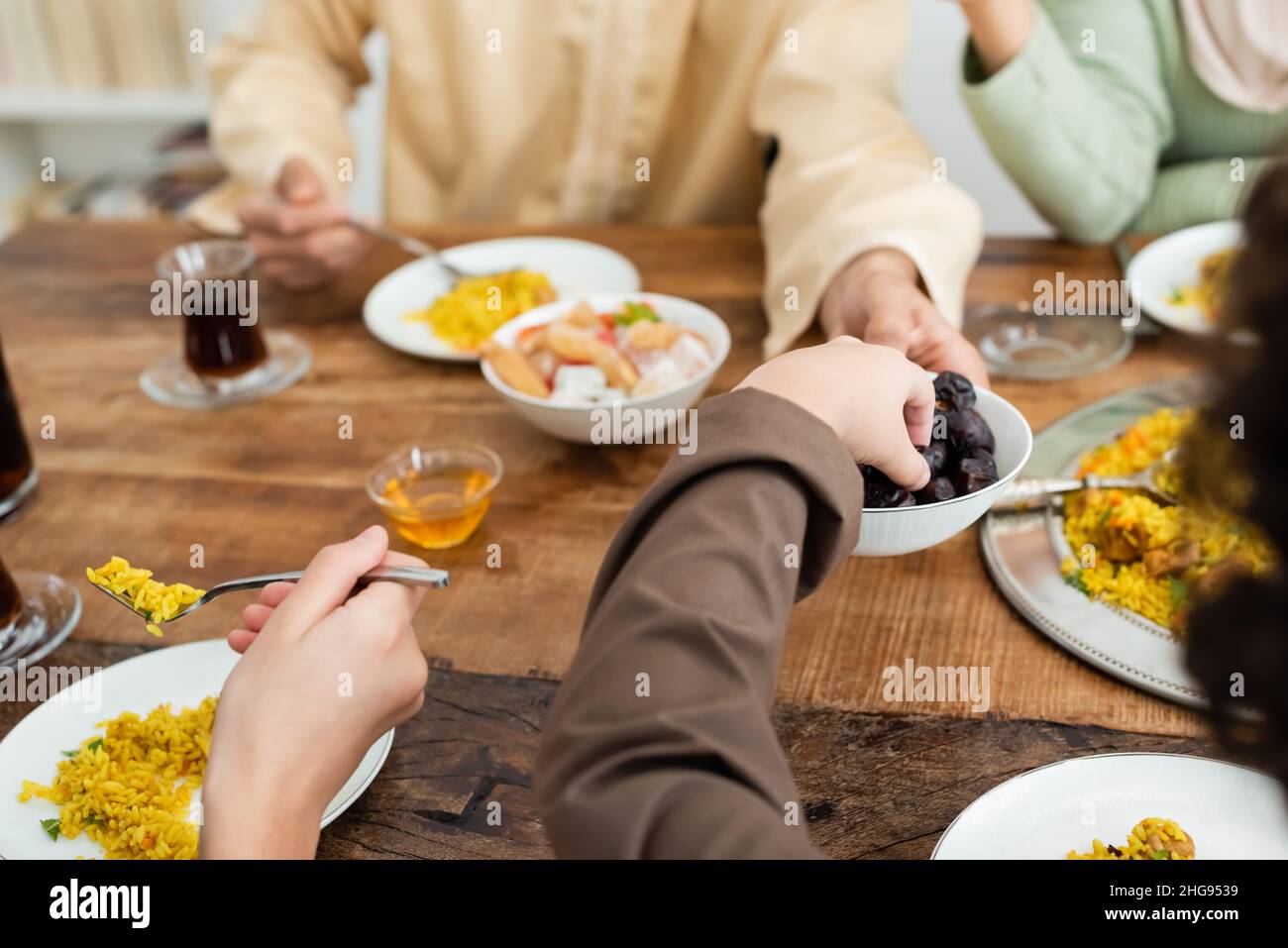 Beschnittene Ansicht des Jungen, der beim Abendessen mit der muslimischen Familie zu Hause Daten erreicht hat Stockfoto