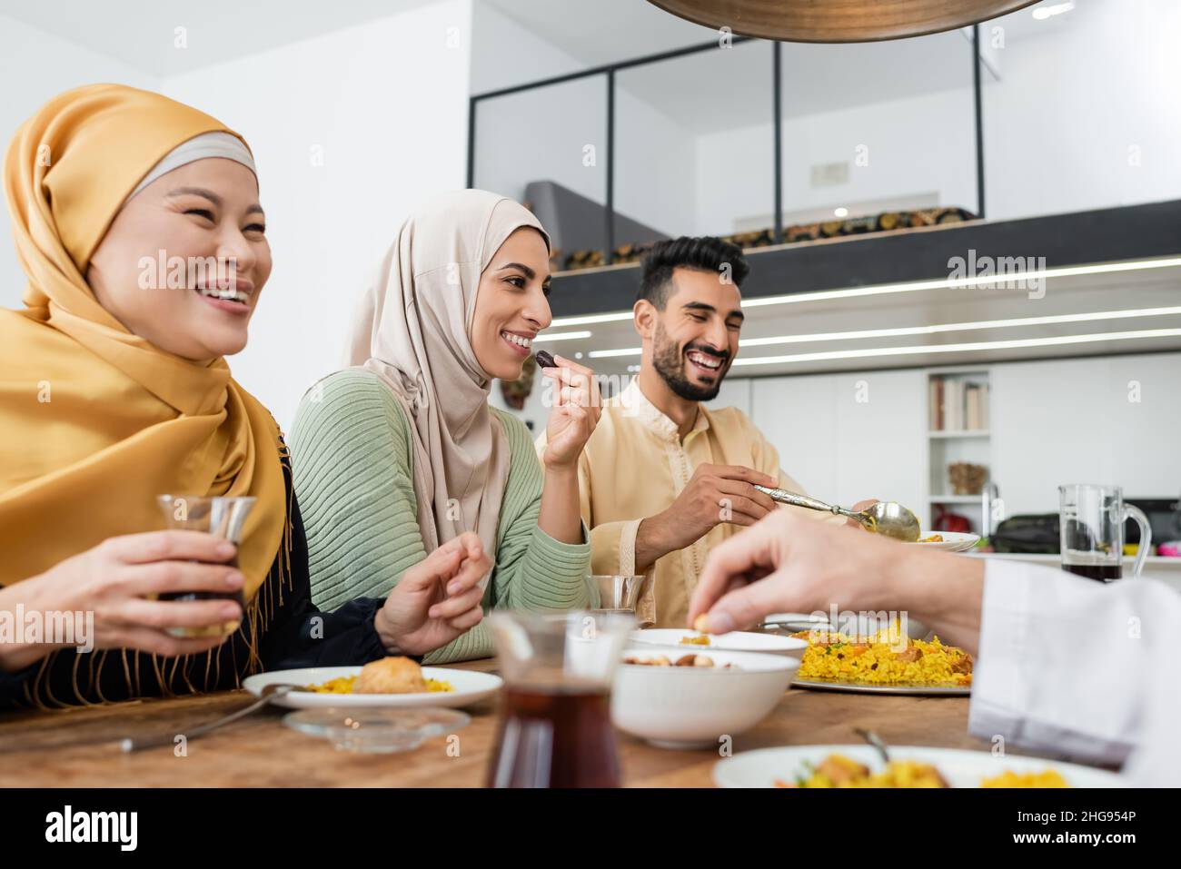 Glückliche arabische Frau, die Dattobst beim Abendessen mit einer multiethnischen muslimischen Familie isst Stockfoto