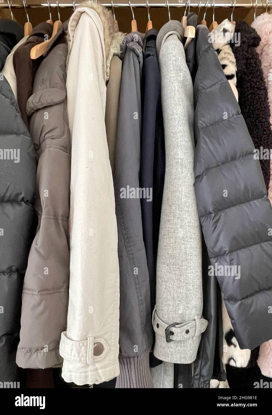 Nahaufnahme verschiedener Jacken und Mäntel, die in einem Kleiderschrank hängen Stockfoto