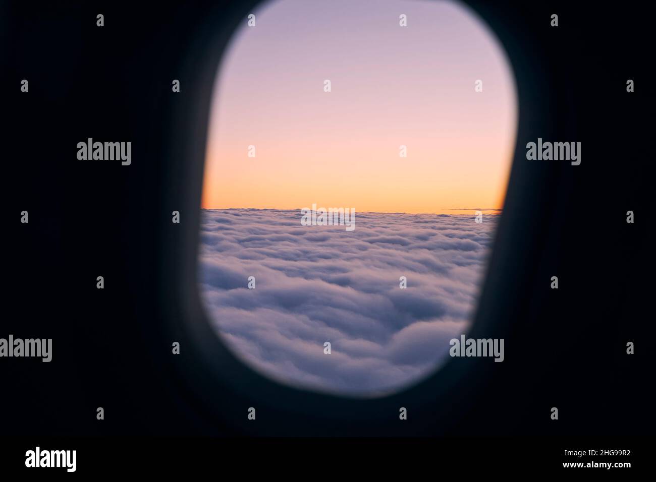 Blick vom Flugzeugfenster während des Fluges über Wolken bei schönem Sonnenuntergang. Stockfoto