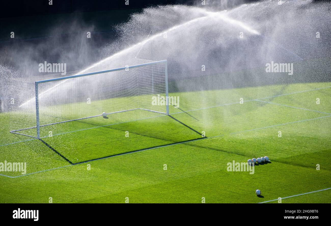 Sprinkler bewässern das Gras durch ein Tor auf einem Fußballplatz Stockfoto