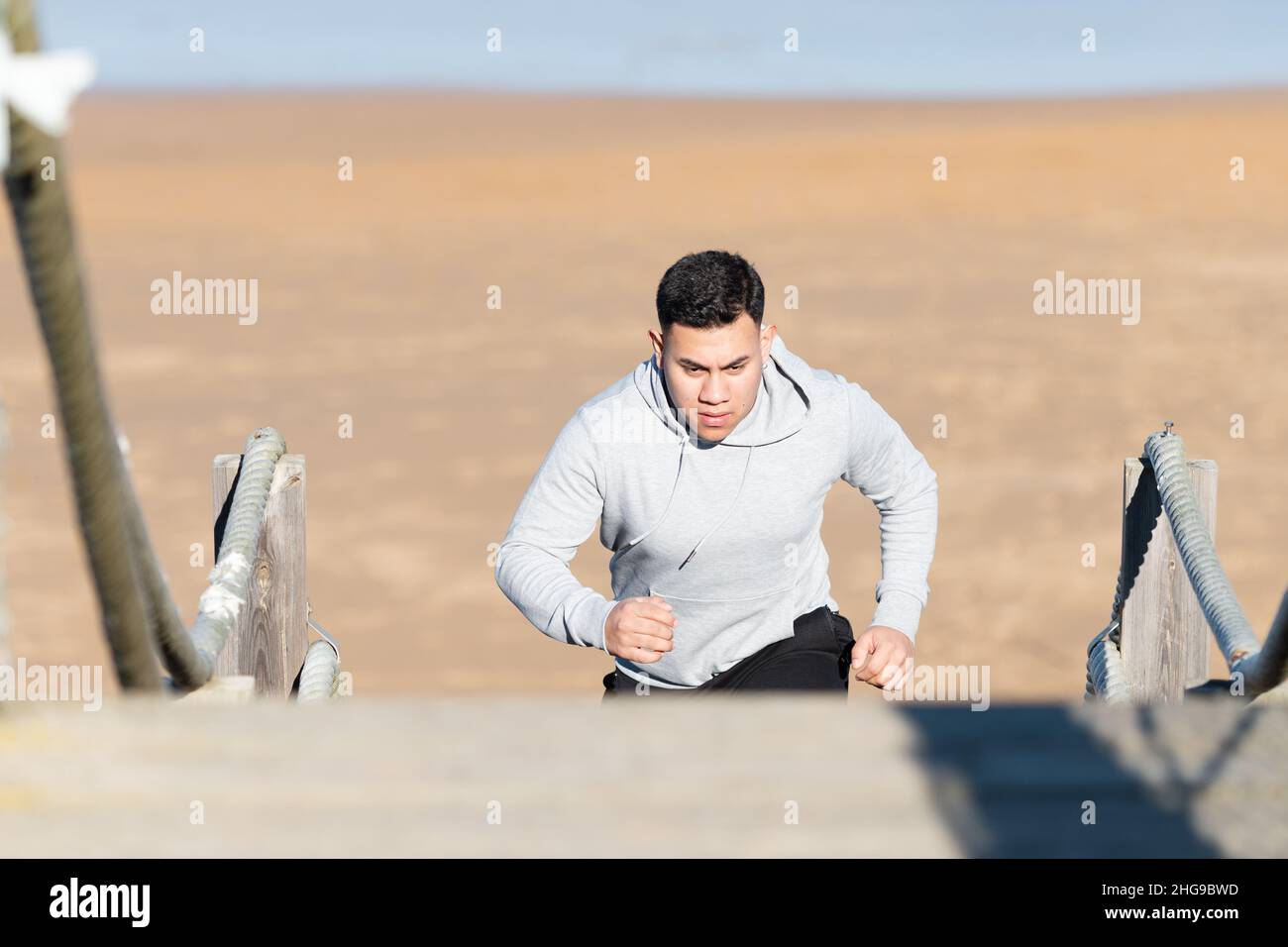 Ein lateinischer Sportler trainiert Kraft auf einer Treppe am Strand Stockfoto