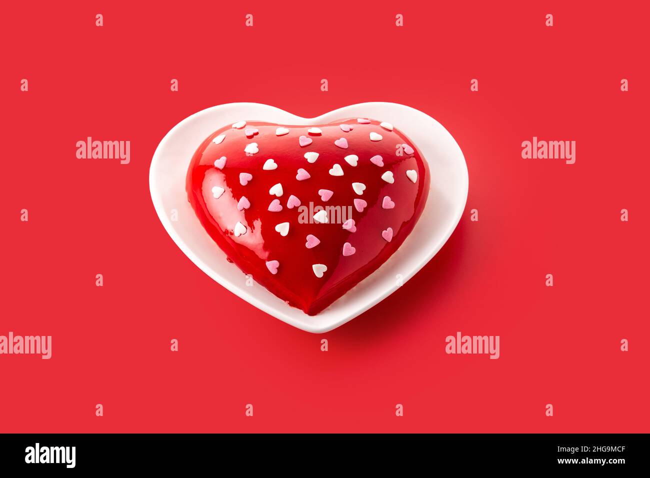 Herzförmiger Kuchen zum Valentinstag oder Muttertag auf rotem Hintergrund. Stockfoto