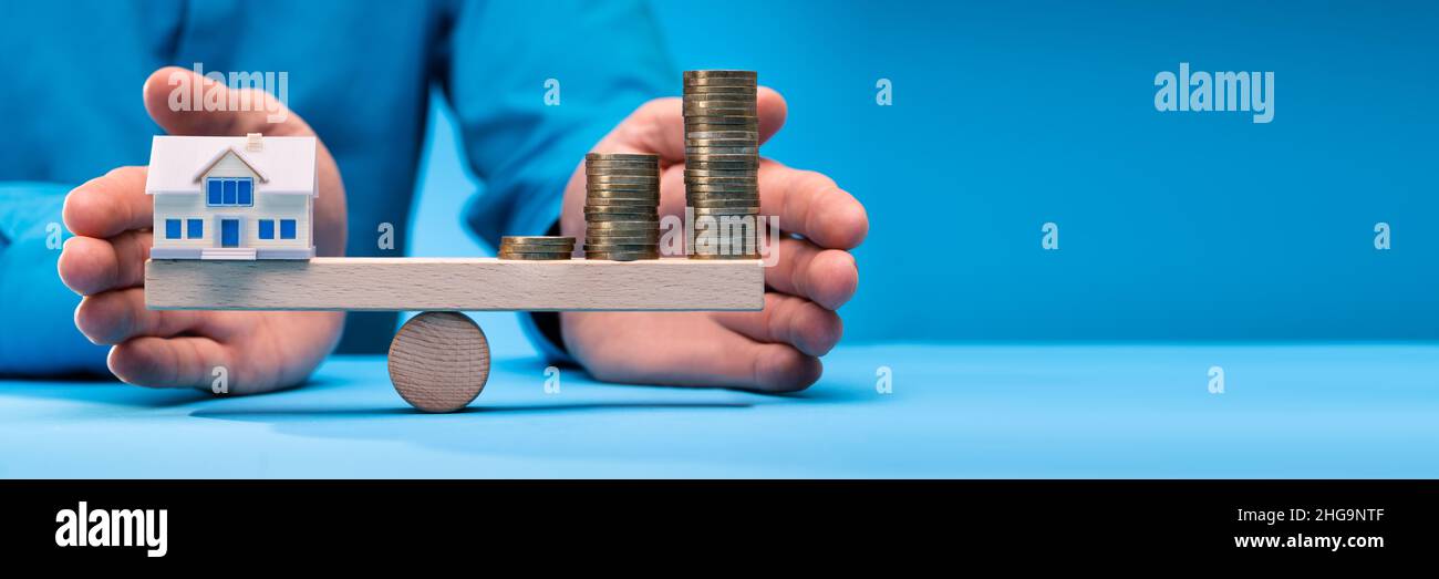 Modell Home und Münzen Balancing auf Holz- Waage Stockfoto