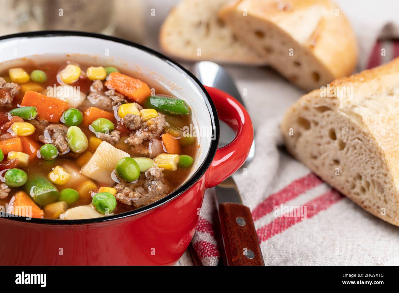 Nahaufnahme der Gemüsefleischsuppe in einer roten Schüssel mit Brotscheiben Stockfoto