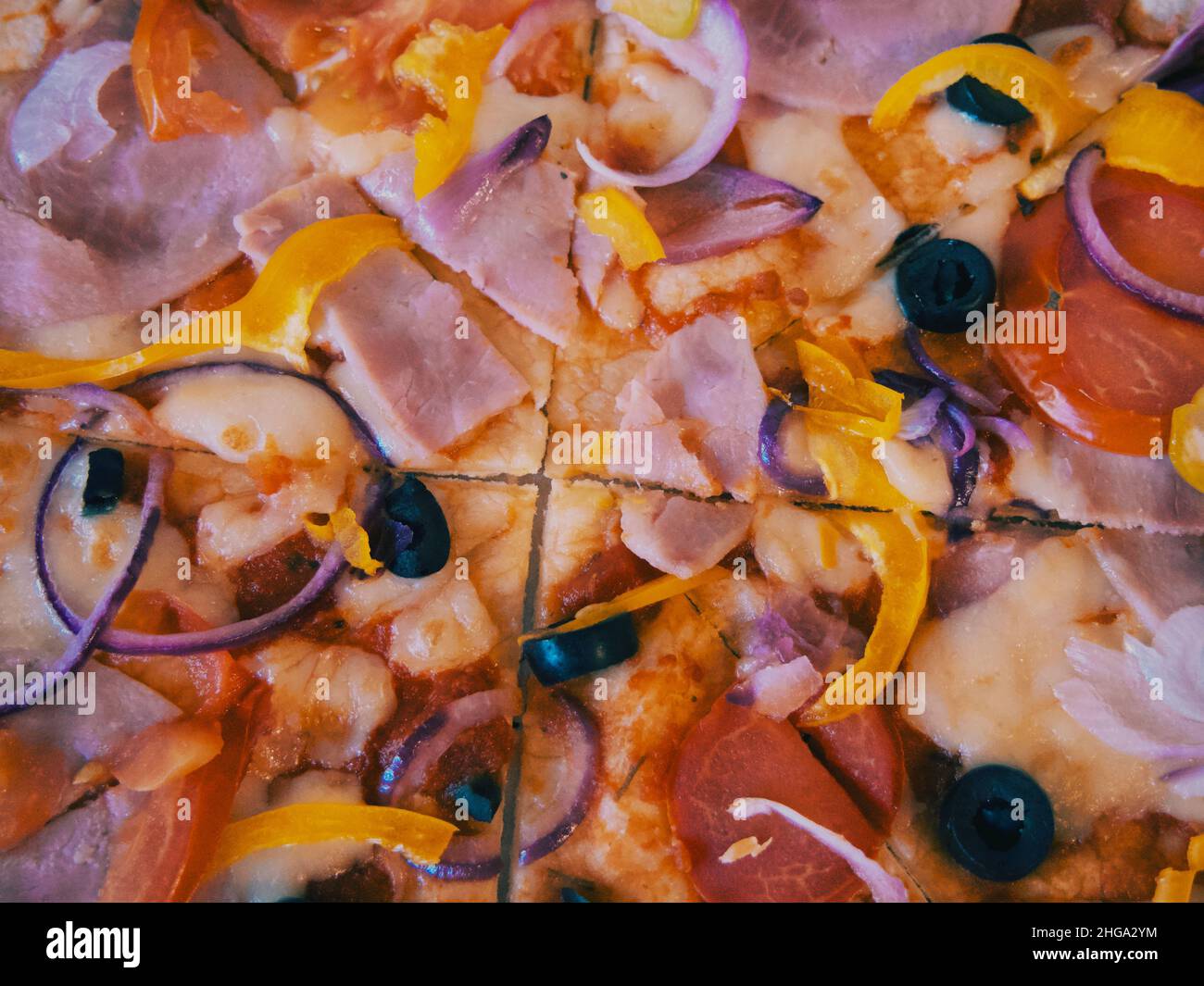 Pizza mit Schinken, Tomaten, Paprika und Oliven, Nahaufnahme. Stockfoto