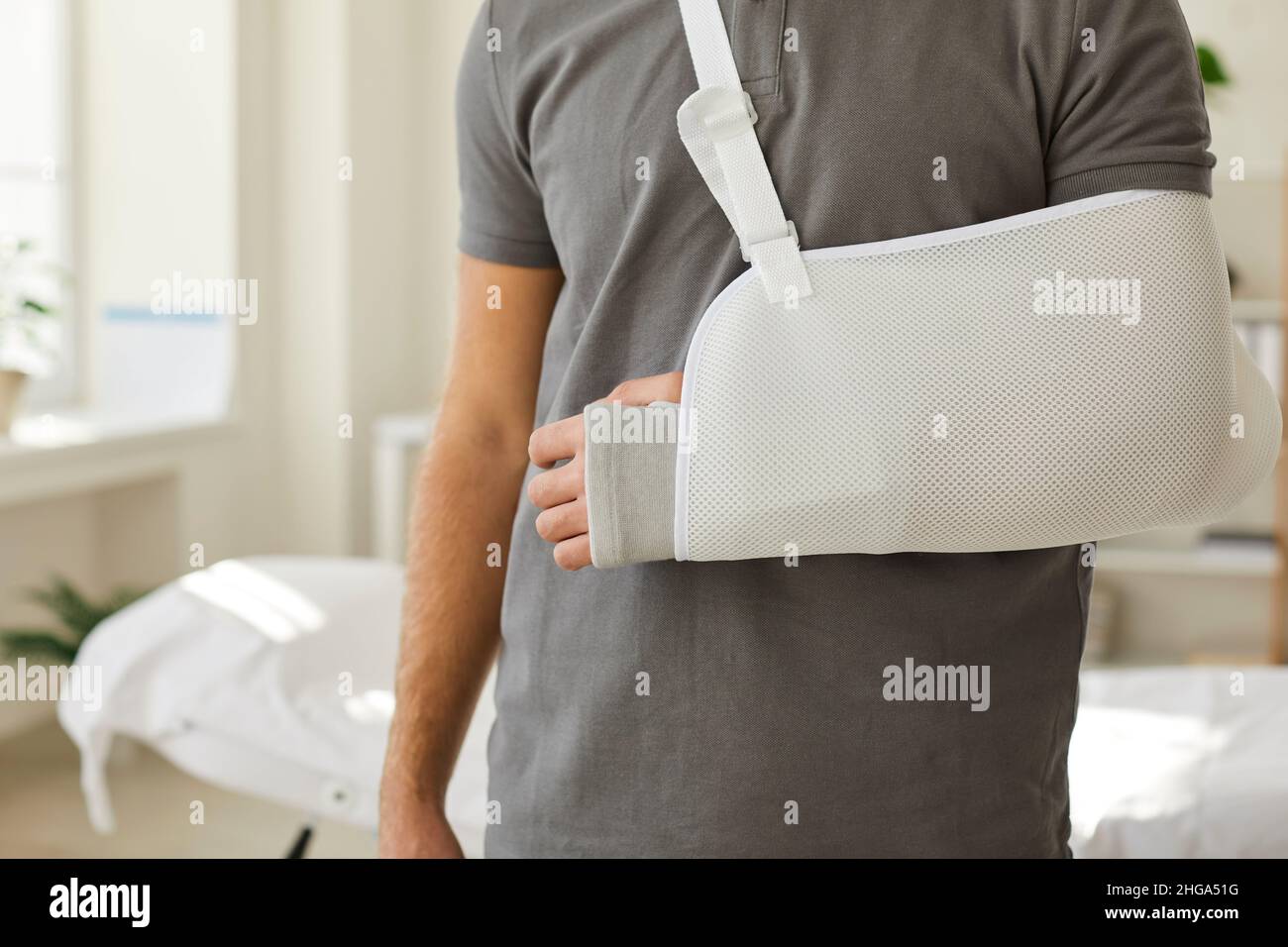 Der Mann trägt einen Hebegurt an gebrochener Hand Stockfoto Der Mann trägt einen Hebegurt an gebrochener Hand Stockfoto