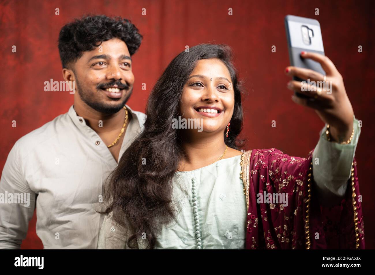 Schönes indisches Paar, das Selfie mit dem Smartphone auf Studiohintergrund macht - Konzept von positiven Emotionen und glücklichen Momenten, Beziehung und Bindung Stockfoto