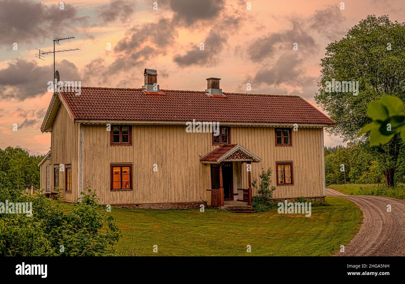 Altes Bauernhaus im Sonnenuntergang mit gelbem Licht in den Fenstern, Mårdaklev, Schweden, 16. juni 2021 Stockfoto