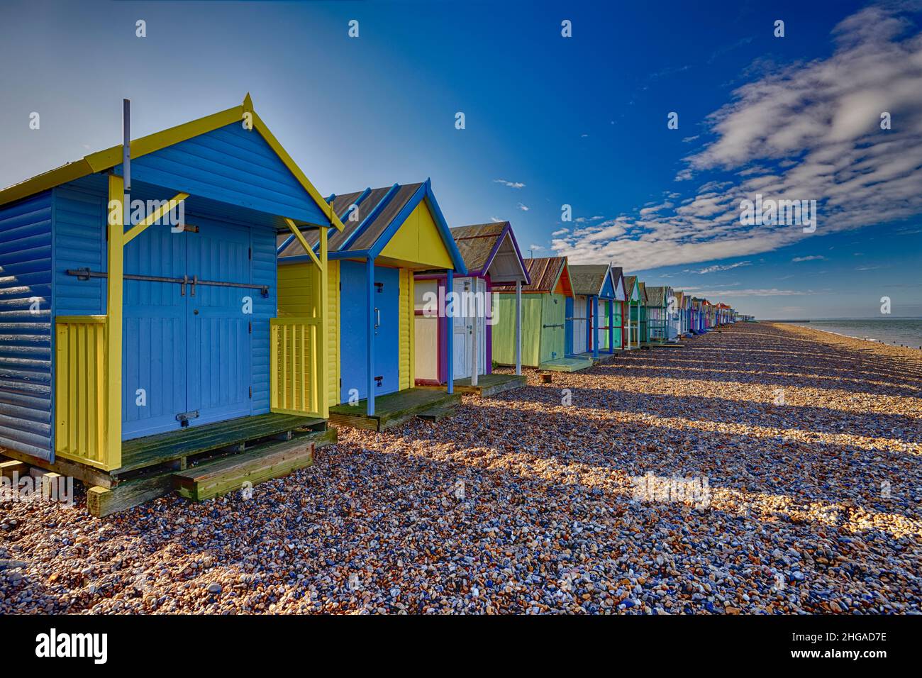 Eine Reihe von farbenfrohen Strandhütten am Kiesstrand der Herne Bay in Kent, Großbritannien Stockfoto