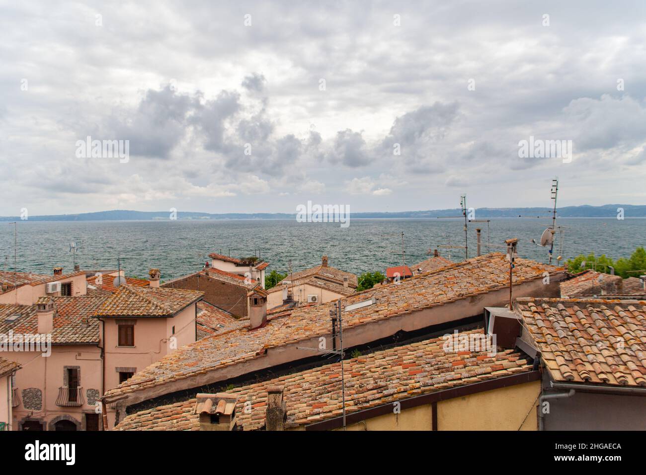 Blick auf den Bracciano-See über die Dächer von Anguillara Sabazia, Latium, Italien Stockfoto