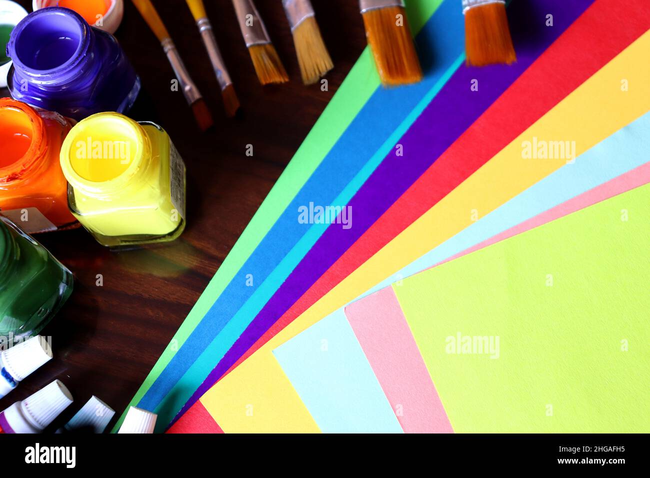 Kunst- und Handwerksausrüstungen, Kunstwerke, Farbpapier, Farbtuben und Pinsel auf einem Tisch, Studentenarbeit Stockfoto