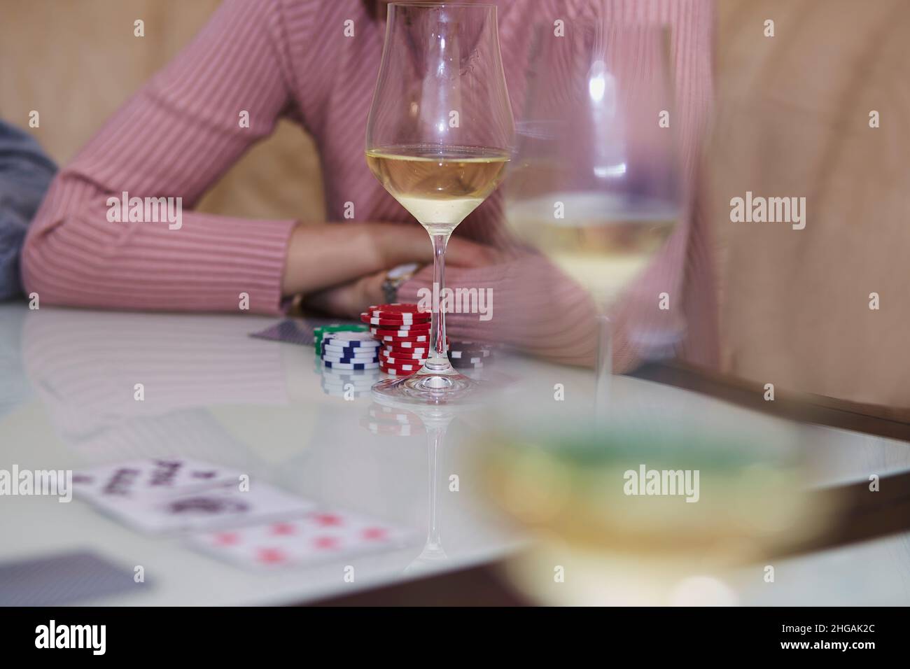 Pokertisch mit Chips, Karten, Gläser Champagner auf dem Tisch mit Reflexion. Genießen Sie den Moment mit Freunden, digitale Entgiftung. Lifestyle-Fotografie. Ehrliche Momente. Selektiver Fokus Stockfoto