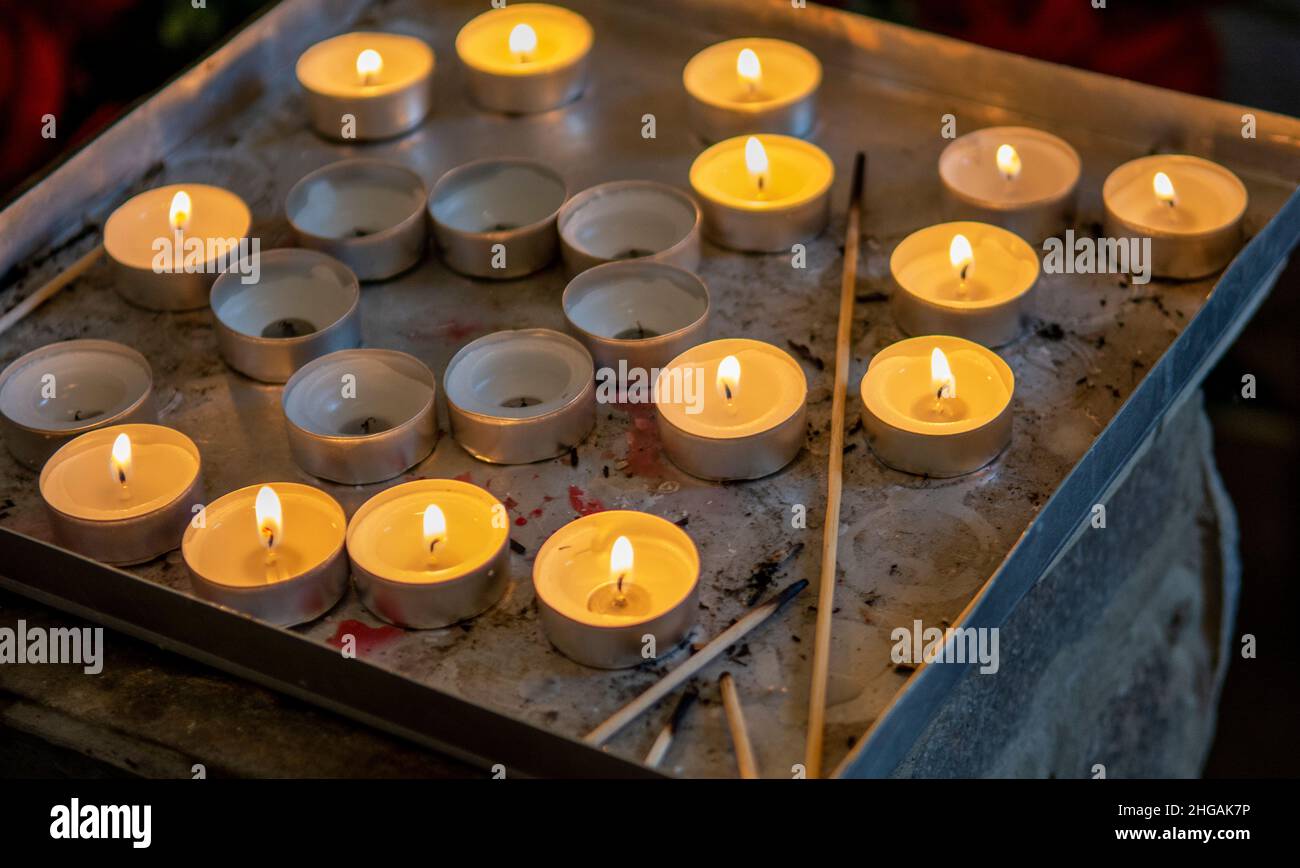 Brennende Gebetskerzen in einer katholischen Kirche. Beleuchtete Teelichter. Selektiver Fokus. Stockfoto