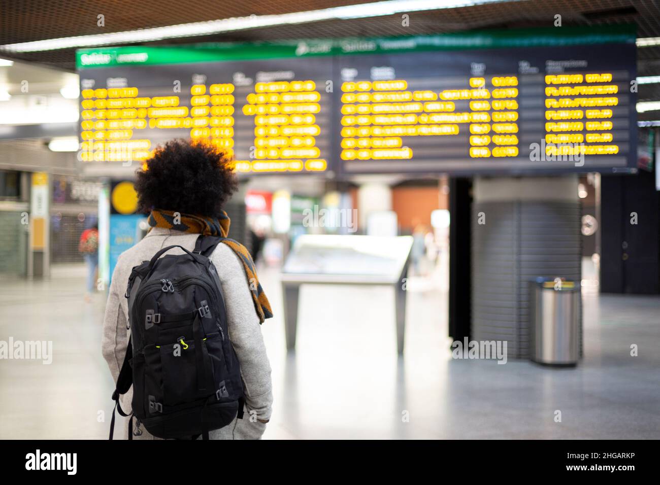 Junge männliche Reisende, die die Abflugs- und Ankunftskonsole am Flughafen oder Bahnhof betrachten. Platz für Text. Stockfoto
